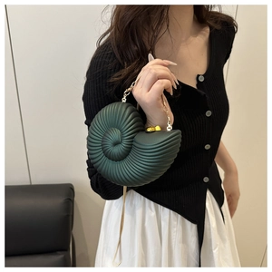 Detail of green conch-shaped acrylic handbag with gold metal clasp and spiral texture