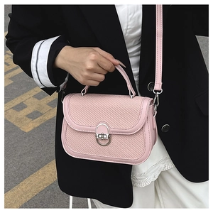 Detail of pink crossbody bag with woven texture, metal lock, and detachable strap
