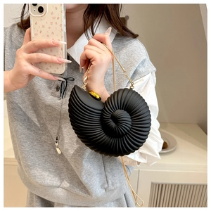 Detailed view of black conch shell bag with golden chain strap and spiral texture