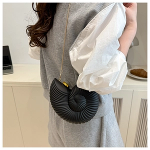 Chic conch shell crossbody bag with golden chain shown in a lifestyle setting