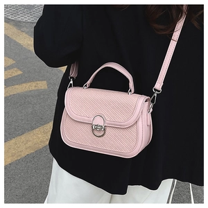 Outdoor shot of pink crossbody bag with textured leather and metal ring buckle detail