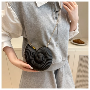 Detail of a black snail shell crossbody bag with acrylic texture and golden chain strap