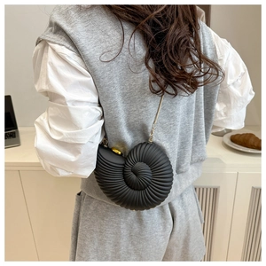 Chic snail shell shoulder bag with gold chain strap shown on model in modern setting