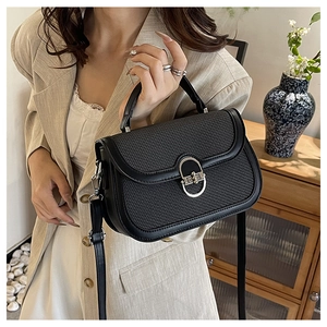 Detail of vintage black woven handbag featuring a silver horseshoe-shaped twist lock buckle