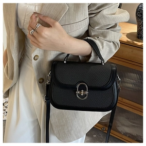Detailed close-up of a black woven crossbody bag with a silver U-shaped metal buckle lock