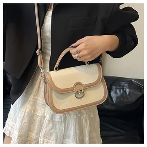Detail of woven fabric handbag featuring a metallic oval lock and adjustable strap