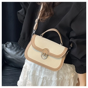 Close-up of retro woven crossbody bag featuring a golden U-shaped metal twist lock