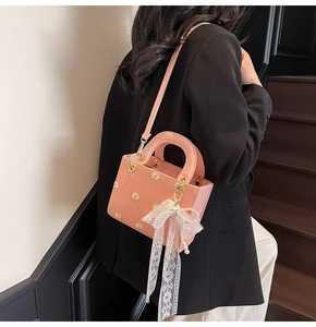 Detail of pink crossbody bag with white daisy prints and pearl lace bow accessory