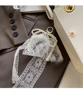 Detailed view of elegant pearl lace bow charm with golden clasp on stylish handbag