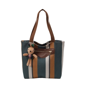Striped tote bag with brown straps and cute rabbit charm on white background