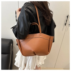 Detailed view of brown leather bucket bag with contrast stitching and sturdy handle
