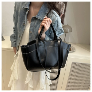 Detail of black leather bucket bag with white contrast stitching and dual strap design