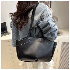 Lifestyle shot of large black tote bag with white contrast stitching on model's shoulder
