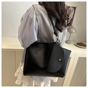 Dettaglio di una borsa tote in pelle nera opaca con taschino frontale e fibbia argento