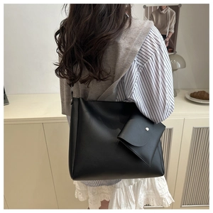 Dettaglio della grande borsa tote nera con pochette coordinata su modella in ambiente moderno