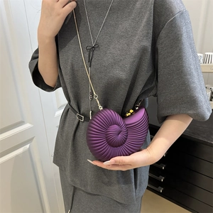 Unique purple nautilus shell crossbody bag with acrylic chain worn by a female model
