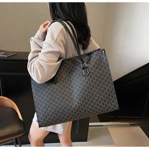 Detailed view of large shoulder tote bag with M-letter monogram pattern on model