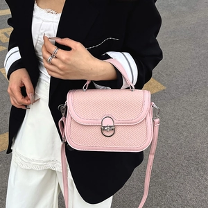 Pink patchwork crossbody bag with woven flap and metal lock shown in street style