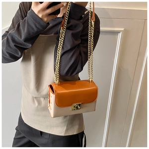 Detail of orange and beige leather crossbody bag with gold chain and rivet accents
