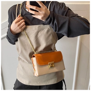 Detail of color-block flap bag with gold star rivets and elegant metal chain strap