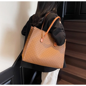 Rear view of a model carrying the large brown M-patterned tote bag on a shoulder