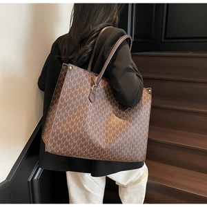 Close-up of brown tote bag featuring luxury monogram pattern and premium leather straps
