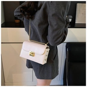 Detail of light pink leather crossbody bag featuring gold hardware and chain strap