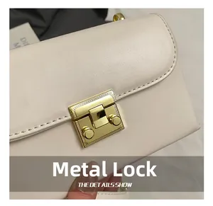 Close-up of elegant gold metal lock with radial engraving on creamy white leather bag