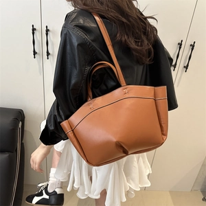 Brown leather bucket bag with gold H-buckle and shoulder strap in a modern setting
