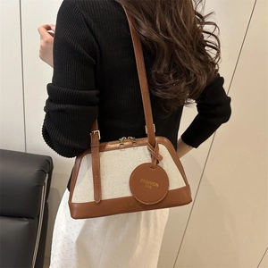 Retro canvas shoulder bag with brown leather trim and golden fashion bag charm tag