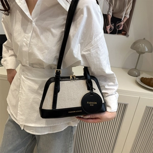 Minimalist canvas shell bag with black leather trim and adjustable shoulder strap