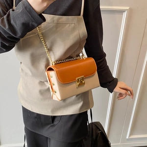 Fashionable orange and beige leather crossbody bag with gold chain strap on model