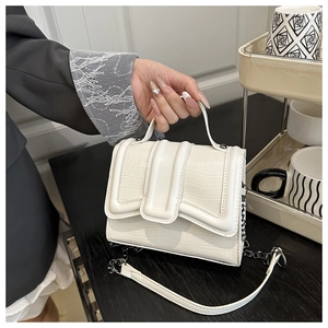 Detail of white stone texture handbag showing faux crocodile embossing and metal chain strap