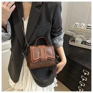 Detailed close-up of brown crocodile texture leather bag with elegant metal chain strap