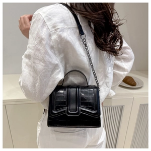 Close-up of black crocodile embossed small square bag with metallic chain strap