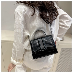 Detail view of black stone texture shoulder bag with metallic chain strap worn by a model
