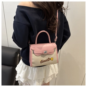 Detail shot of a pink leather and beige canvas Kelly bag worn by a model in casual attire