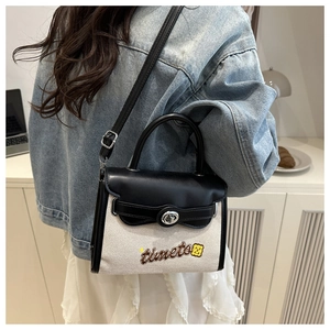 Detail of contrast Kelly bag showing black leather flap, canvas mix and bear embroidery