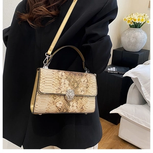 Dettaglio borsa beige con trama a serpente e chiusura magnetica a testa di leone in argento