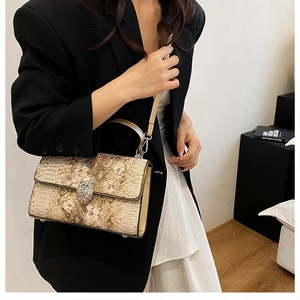 Dettaglio borsa beige con stampa serpente e chiusura a leopardo con strass argentati