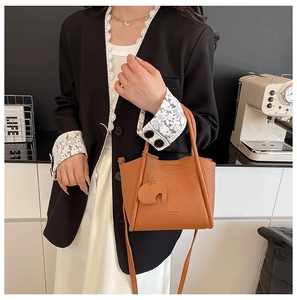 Detailed view of brown lychee grain leather bucket bag with cute elephant charm