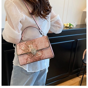 Dettaglio borsa rosa con motivo a serpente e chiusura a testa di leone su camicia bianca