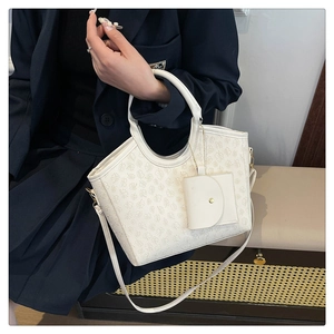 Detailed shot of white faux leather bag with clover texture and mini pouch accessory