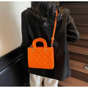 Borsa a tracolla quadrata trapuntata arancione brillante abbinata a un blazer nero