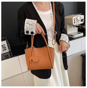 Detail of brown litchi pattern leather bucket bag with elephant charm and strap