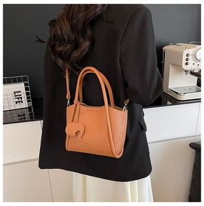 Close-up of caramel lychee leather handbag with shoulder strap in a modern kitchen setting