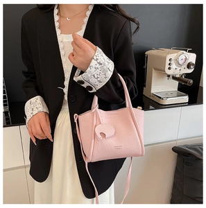 Close-up of pink litchi grain leather tote bag featuring a cute elephant charm