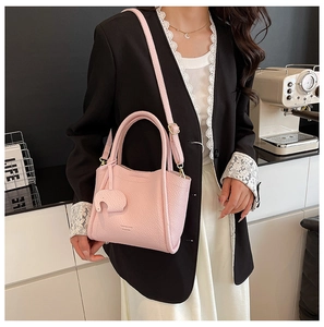 Detail of pink lychee leather bucket bag with elephant charm and Happiness Bag text