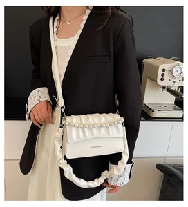 Detail of white pleated bag featuring pearl chain handle and fashion branding text