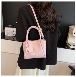 Detail of pink lychee leather bucket bag with elephant charm and brand embossing